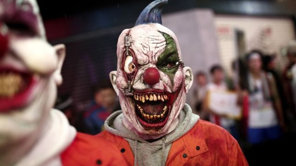 Persona con máscara de payaso grotesco en una celebración de Halloween